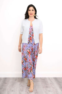 Woman in a light buttoned cardigan over a purple floral jumpsuit
