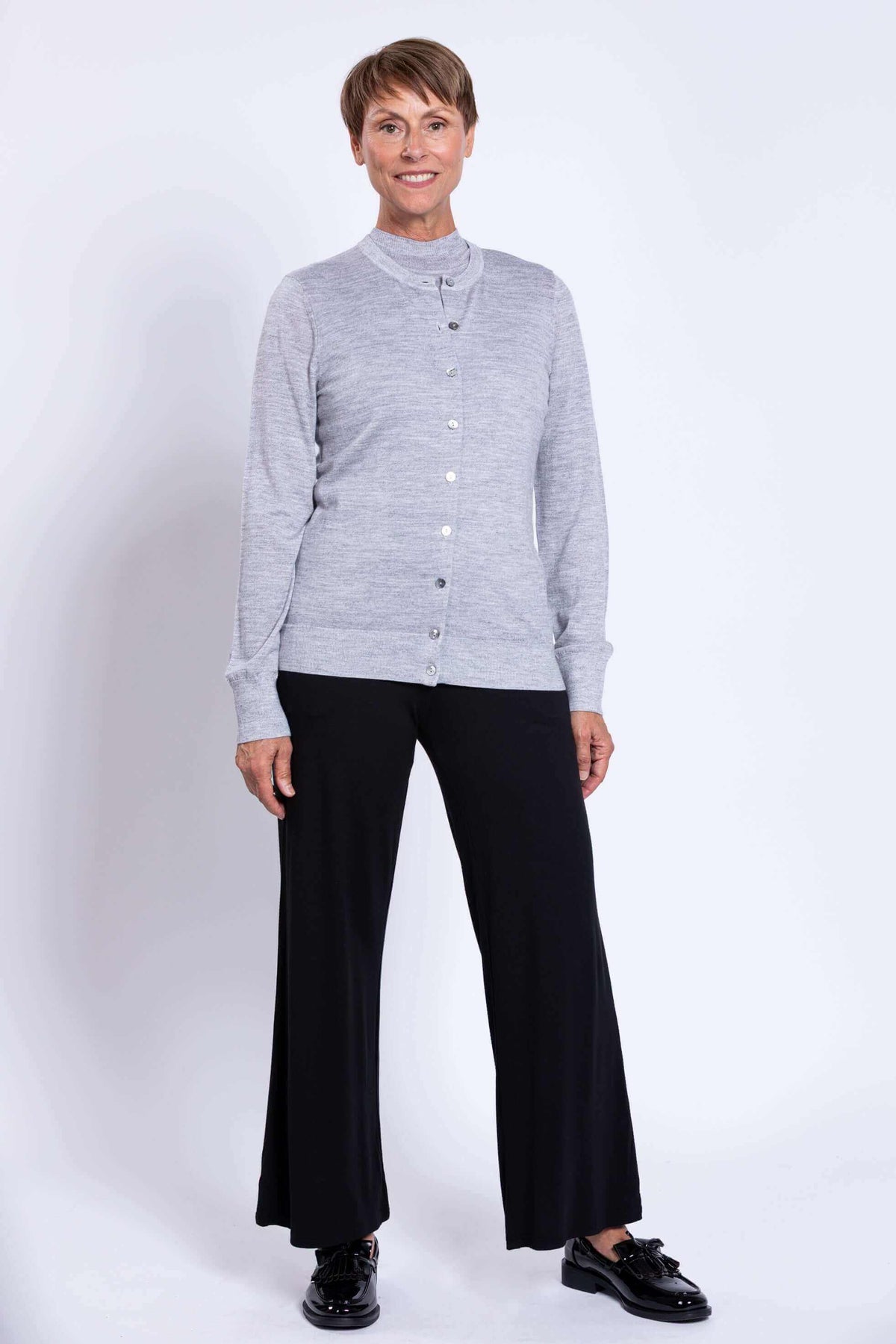 Woman wearing a light grey merino wool button-up cardigan with black pants