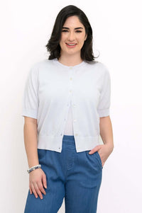 Front view of woman modeling a light short-sleeve buttoned cardigan with blue pants