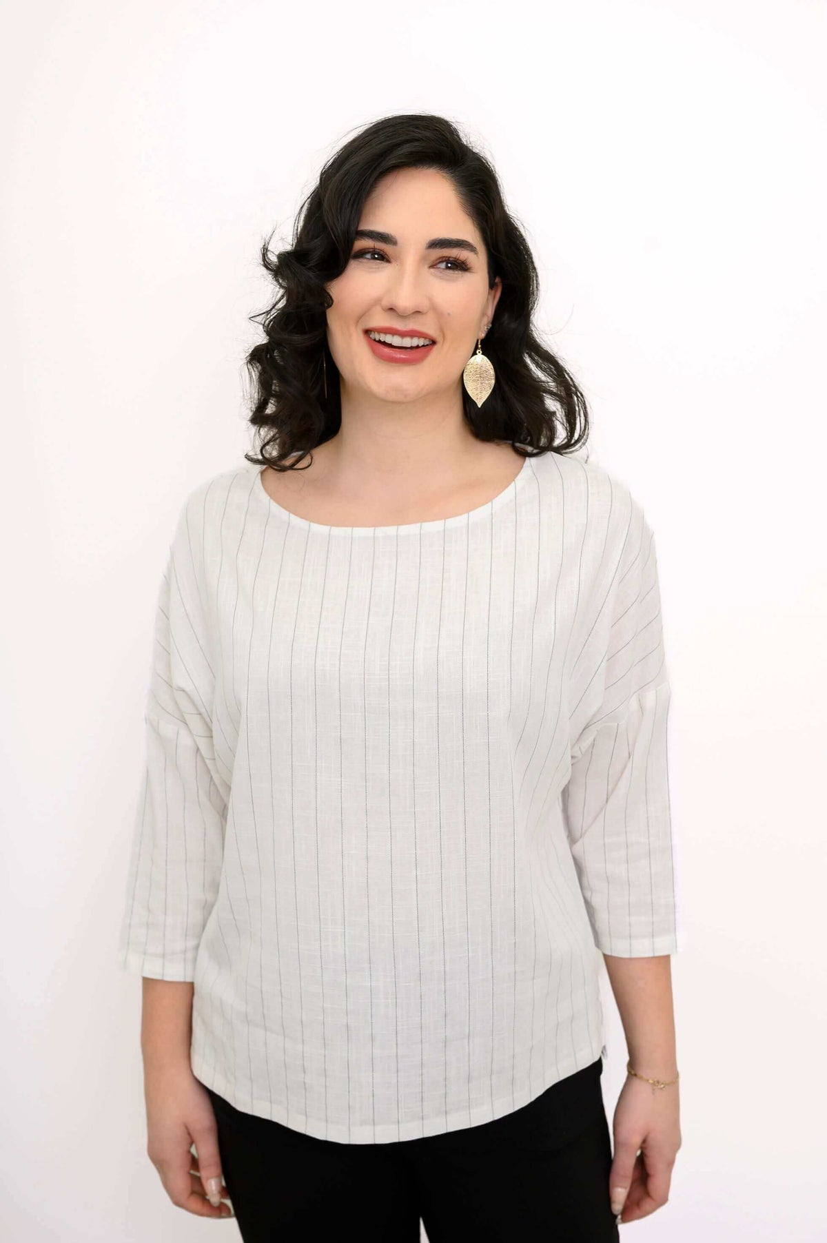 Woman wearing a light striped linen-blend top with drop shoulders and 3/4 sleeves, smiling