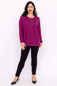 Woman in a magenta Merino wool sweater and black slim pants, smiling