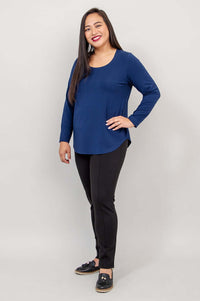 Woman in navy blue long sleeve top and black pants, angled view