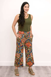 Woman in olive tank top and colorful floral wide leg pants with hands in pockets