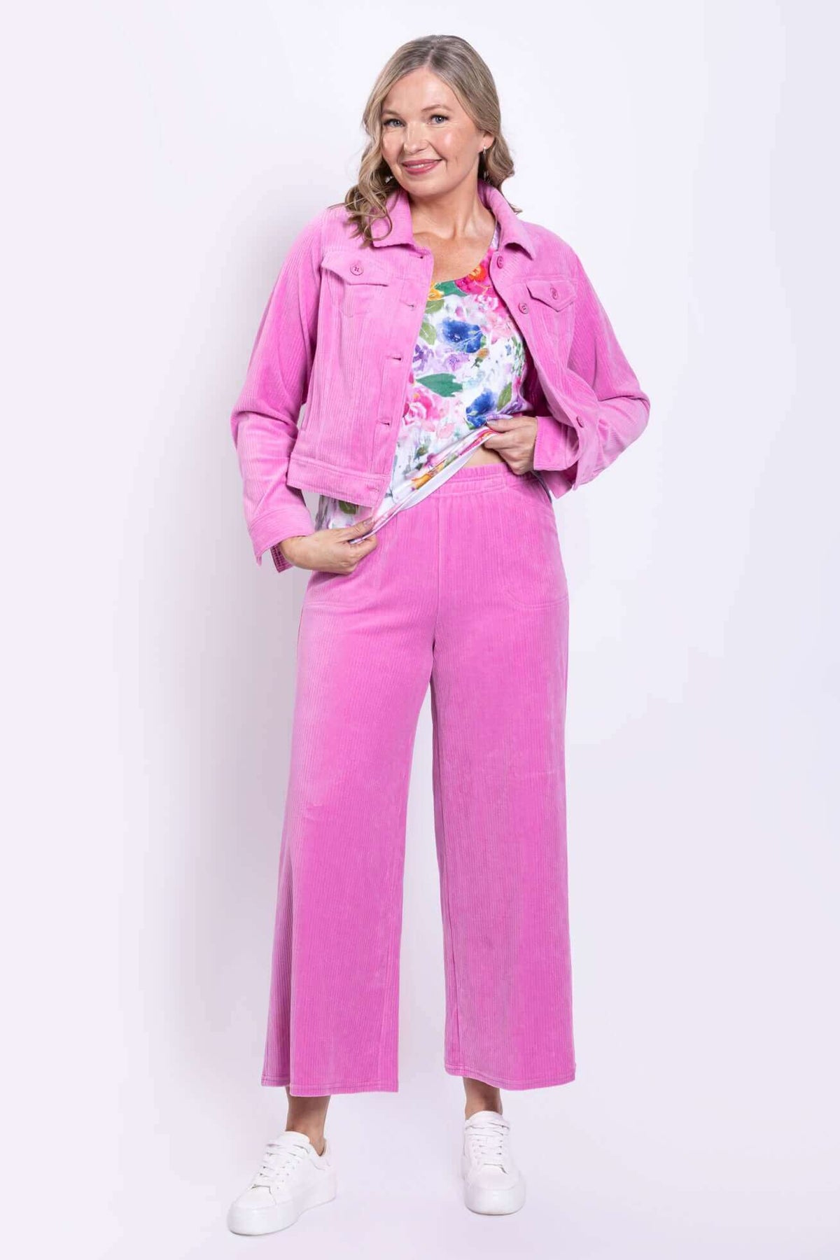 Woman wearing pink corduroy wide-leg pants and matching jacket with floral top