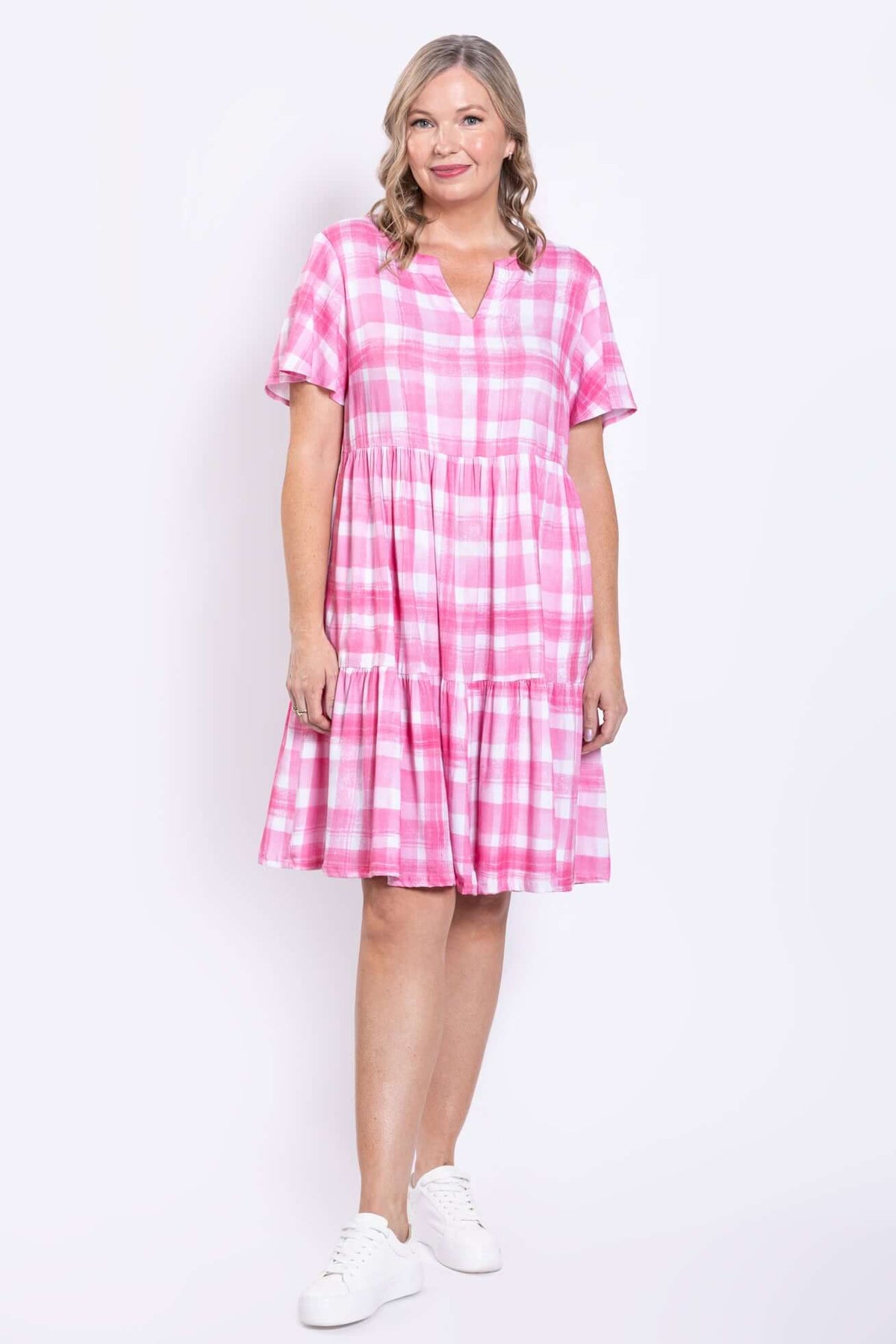 Woman posing in pink gingham plaid dress, standing at an angle
