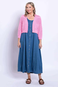 Woman smiling in a pink pointelle cardigan layered over a denim dress