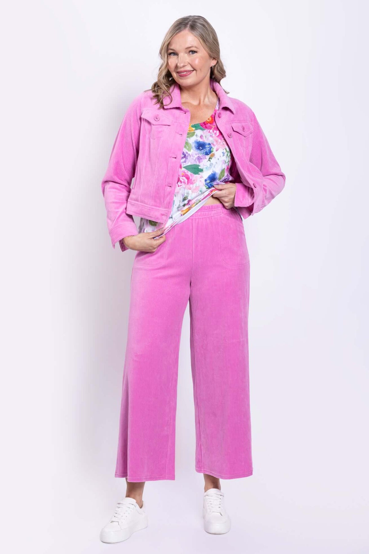 Woman wearing bright pink wide-leg pants with a matching jacket and floral top