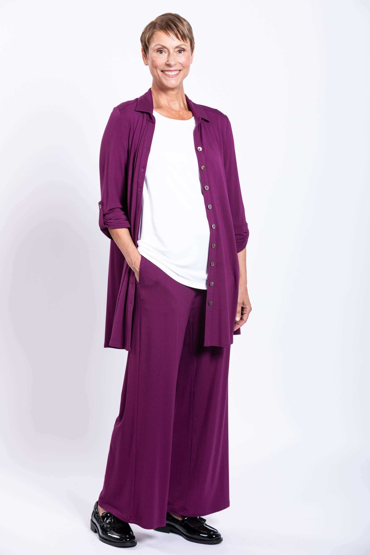 Woman wearing a purple button-up bamboo tunic over a white top with matching pants