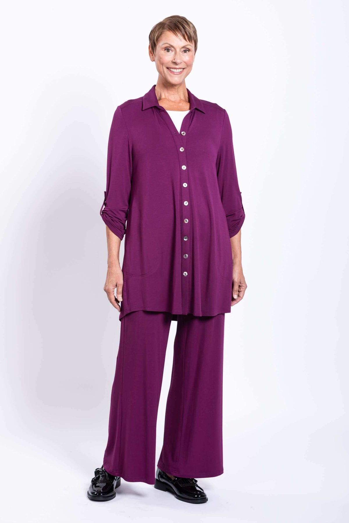 Woman in a purple button-up bamboo tunic and matching pants, smiling at the camera