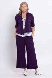 Woman layered in a purple open cardigan over a white and purple floral tank with matching pants