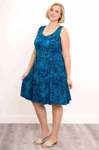 Woman wearing a sleeveless blue A-line dress with tropical leaf print