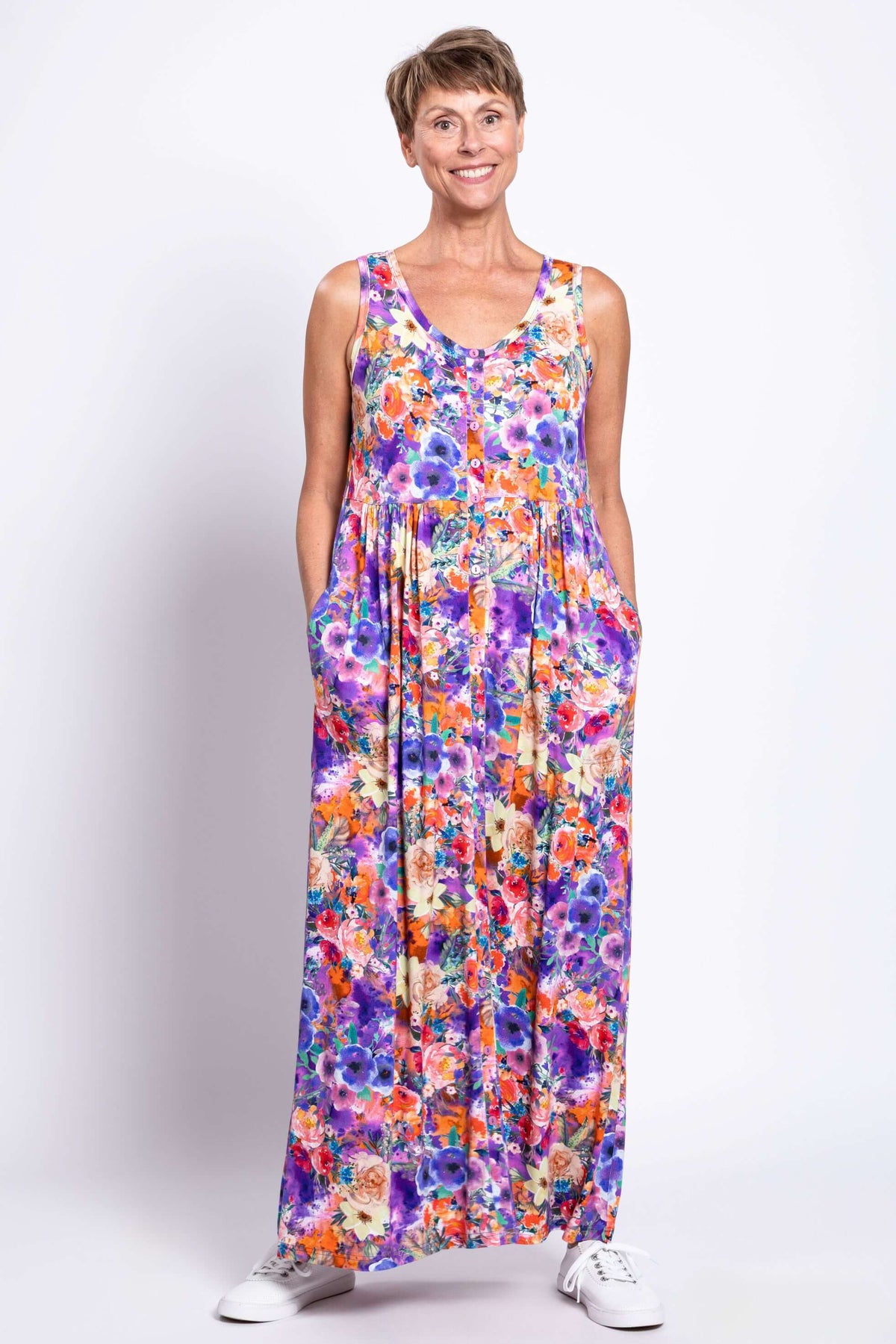 Woman smiling and wearing a sleeveless floral maxi dress with pockets, front view