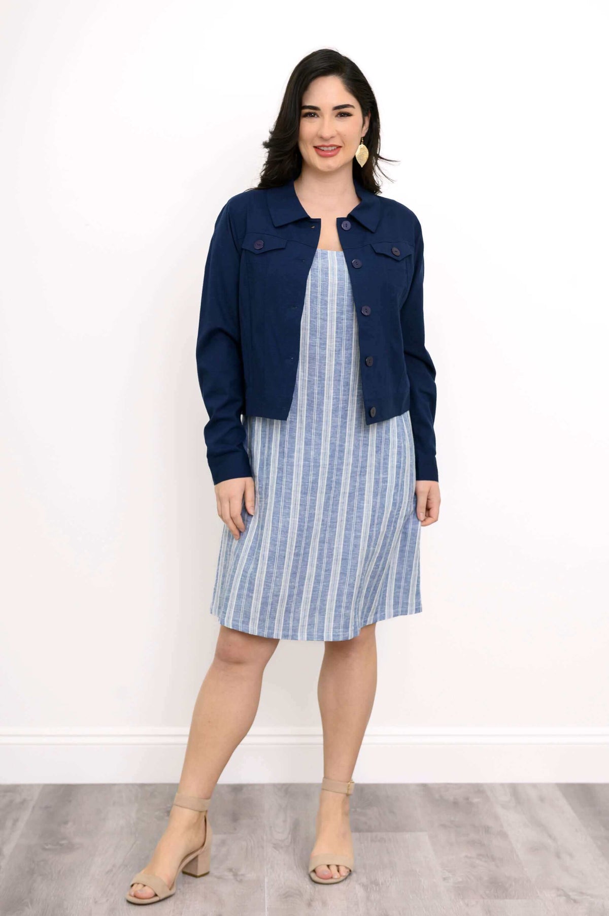Woman wearing blue and white shift dress paired with a navy jacket.