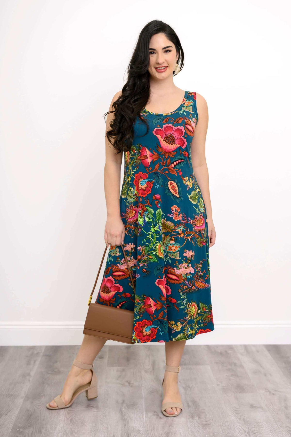 Woman wearing a sleeveless teal midi tank dress with vibrant floral pattern