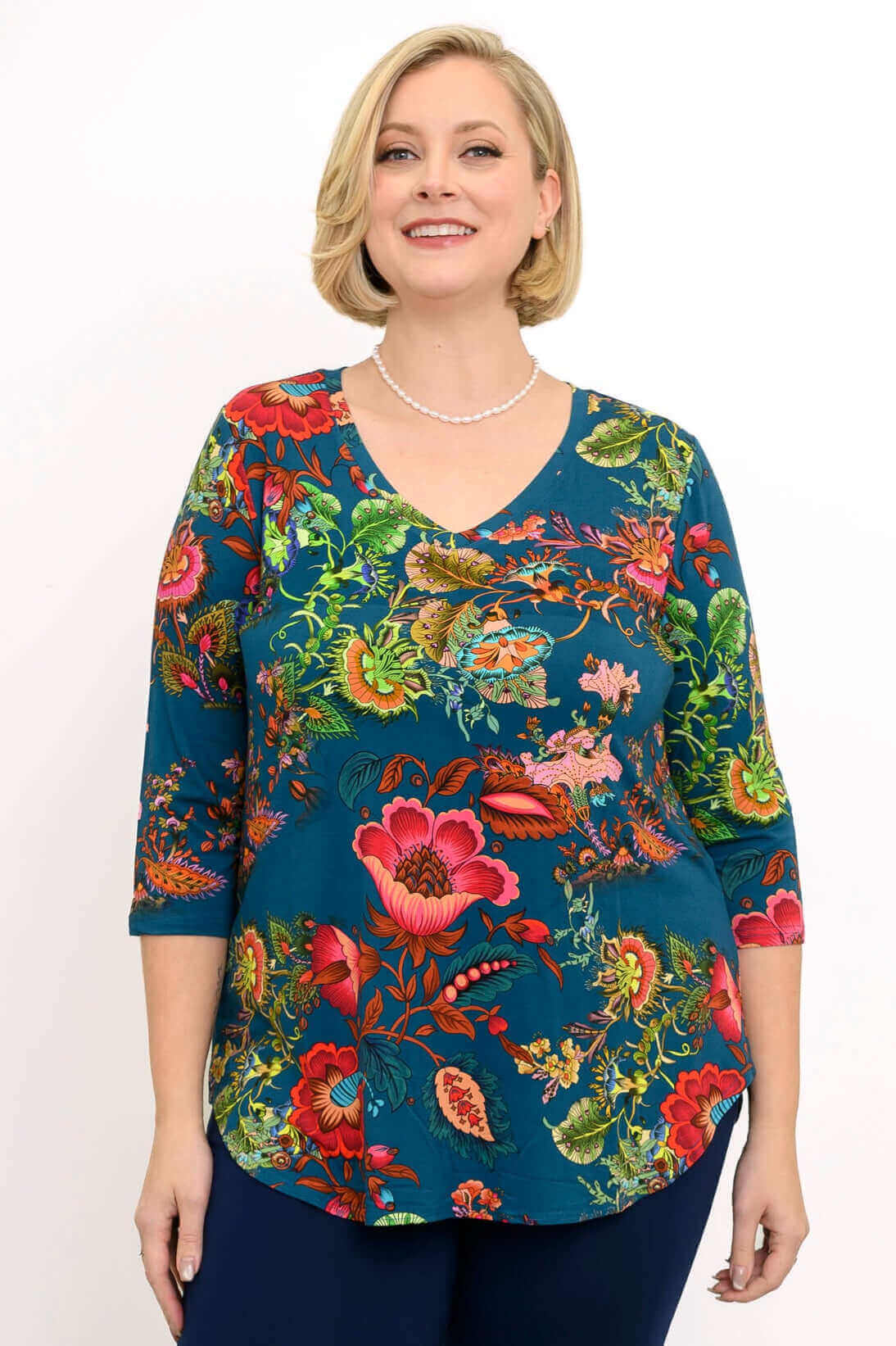 Woman in a vibrant blue V-neck top with bold floral print and three-quarter sleeves