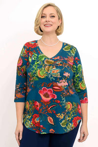 Woman in a vibrant blue V-neck top with bold floral print and three-quarter sleeves
