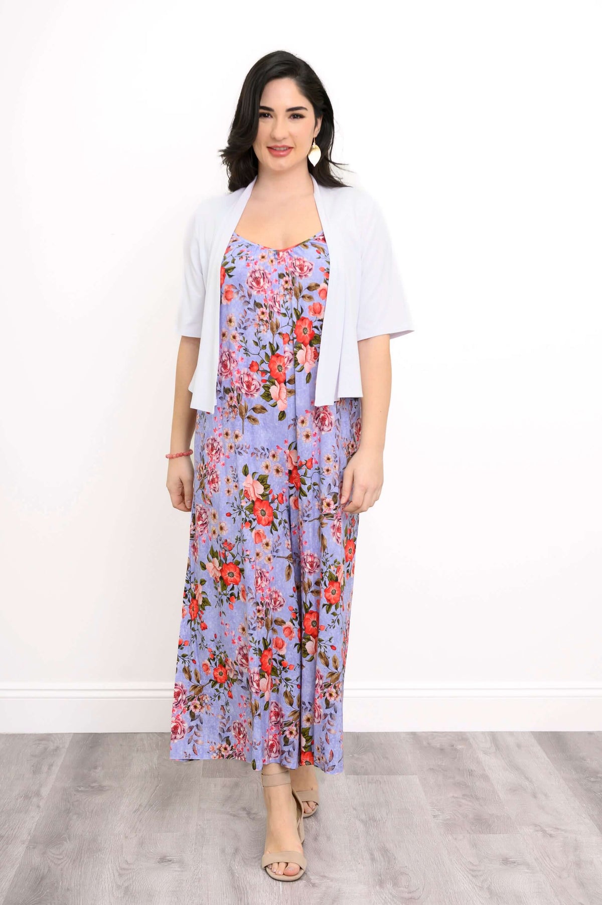 Woman layering a white cropped cardigan over a purple floral jumpsuit