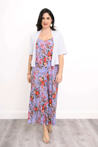 Woman layering a white cropped cardigan over a purple floral jumpsuit