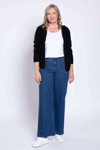Front view of woman in wide leg blue jeans, white shirt, and black hoodie