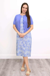Woman layered in a blue buttoned shrug over a light blue floral midi dress