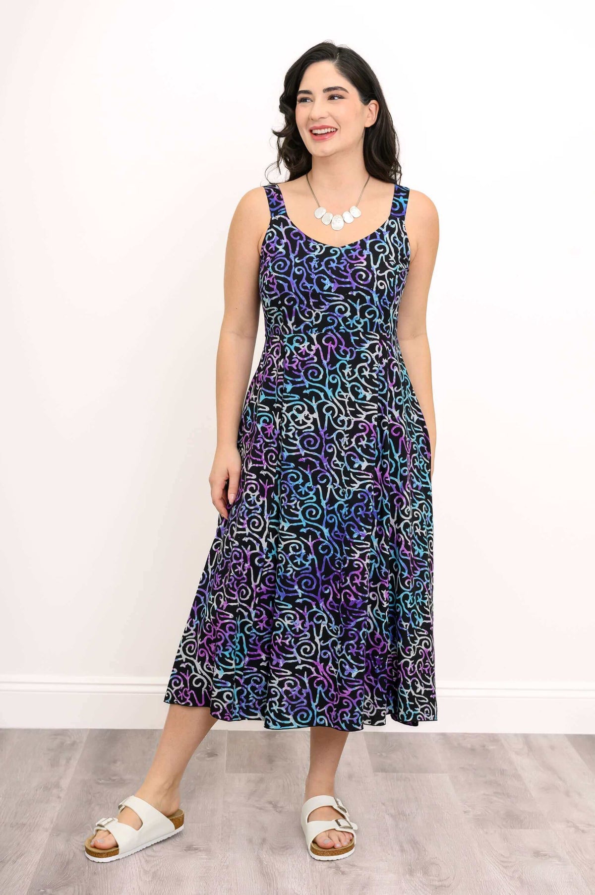 Woman in a patterned A-line dress looking to the side, hands in pockets