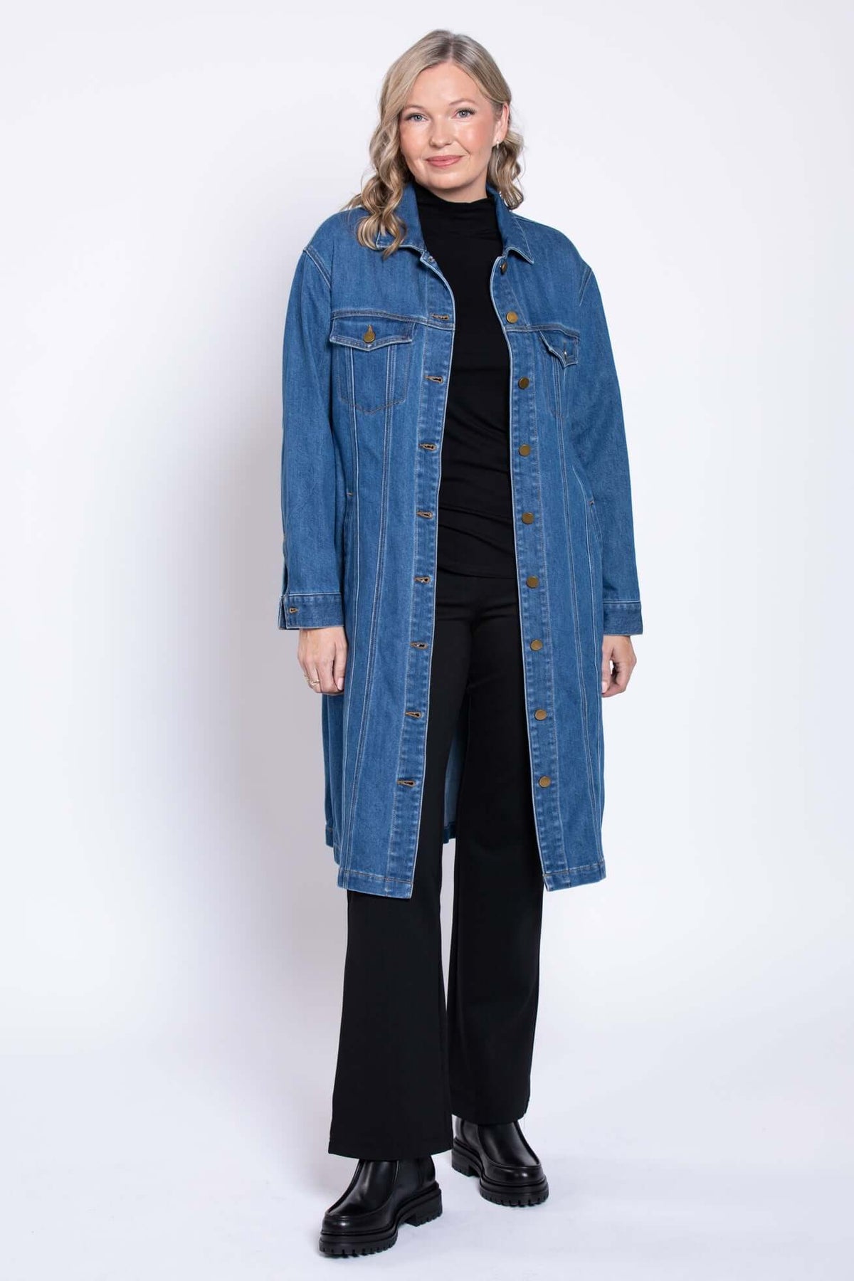 Woman modeling Geraldine denim jacket, buttoned front, with black pants and boots