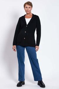 Woman standing in the Margaret Jacket, black knit with gold buttons and front pockets
