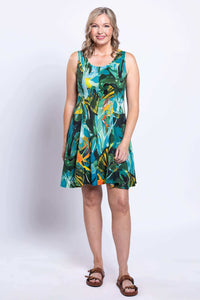 Woman posing in a sleeveless knee-length dress with green and blue leafy pattern, facing forward