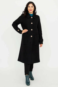 Woman modeling a black Edna coat with collar, full sleeves, and buttoned front