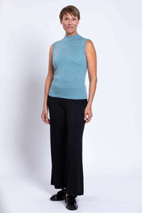 Woman modeling a blue sleeveless merino sweater with black pants and loafers