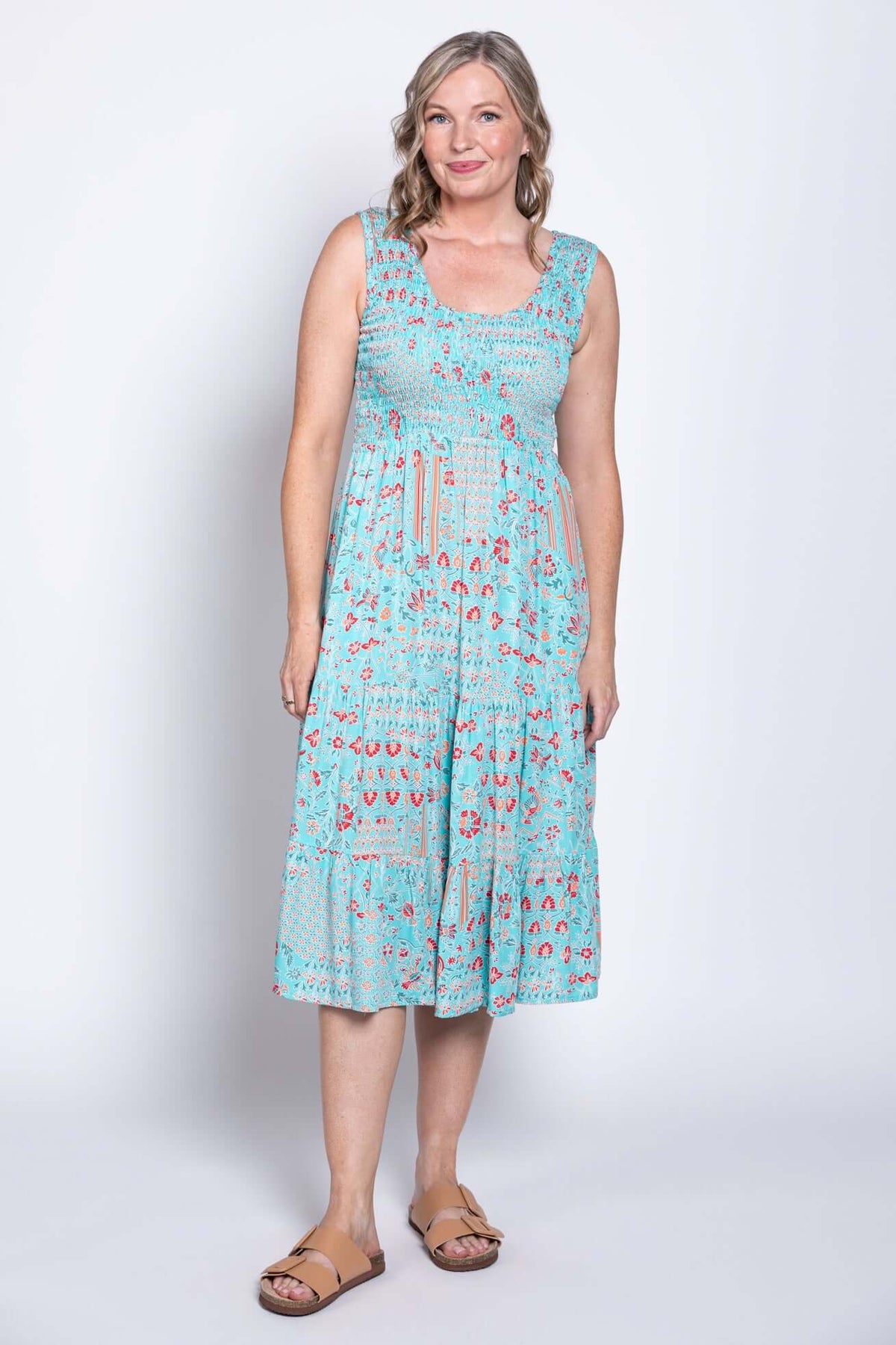 Woman modeling a blue tiered floral dress, angled slightly to the side