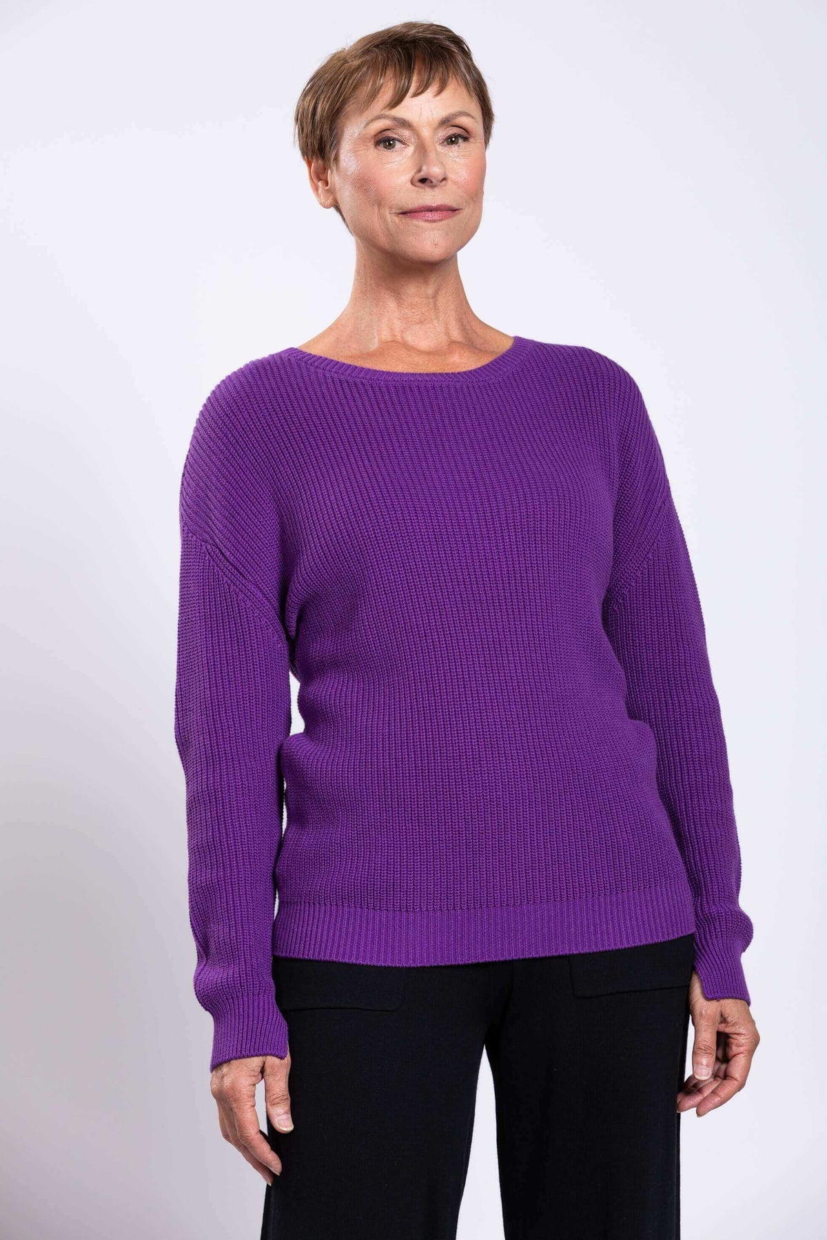 Woman modeling a purple shaker stitch cotton sweater and black pants