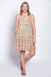 Woman modeling a sleeveless tiered dress with fruit and sun pattern, standing at an angle