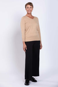 Woman modeling beige V-neck pullover sweater with black trousers