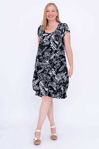 Woman modeling black and white leaf print dress, front view