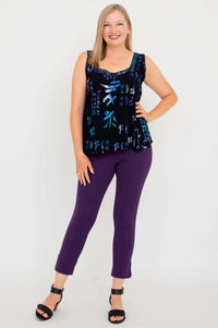 Full body view of woman in black batik sweetheart tank top paired with purple pants and sandals
