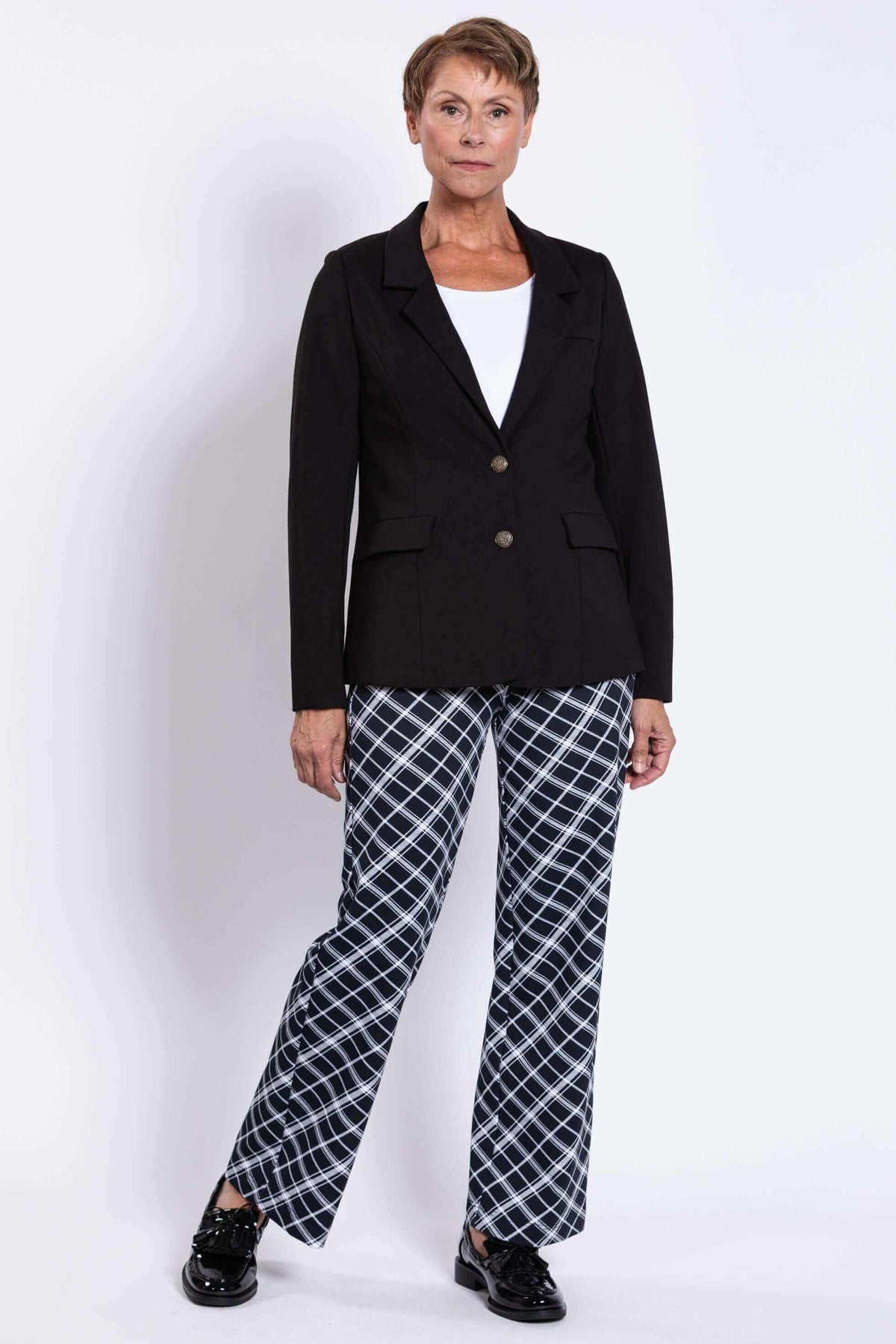 Woman modeling black blazer and checked pants, relaxed stance, front view