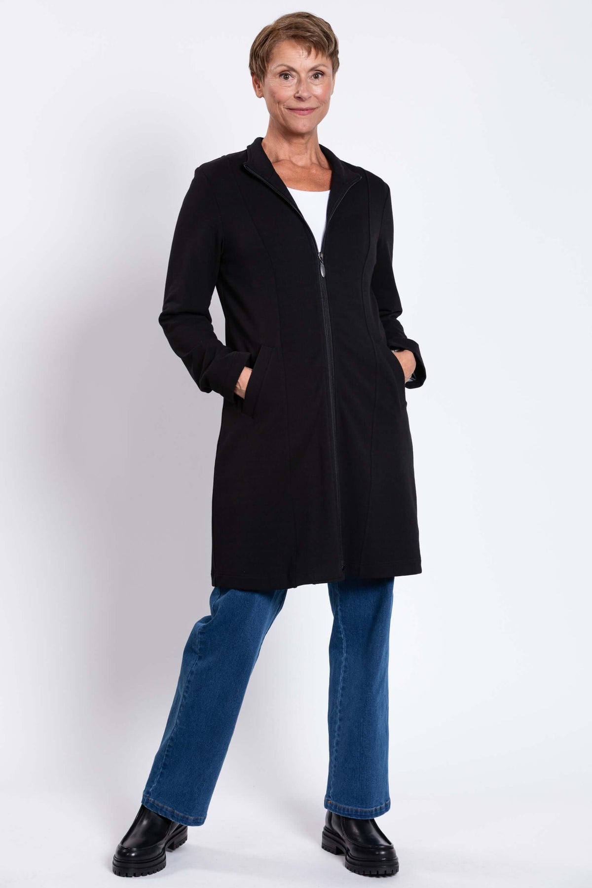 Woman modeling black coat with hands in pockets and relaxed stance