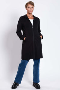 Woman modeling black coat with hands in pockets and relaxed stance