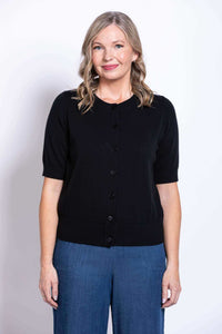 Woman wearing a black short-sleeve button-up cardigan and blue wide-leg pants, front view
