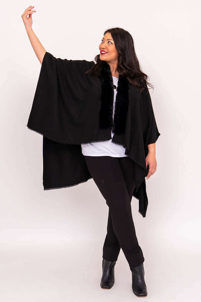 Woman posing with arm raised while wearing a black wrap with faux fur collar