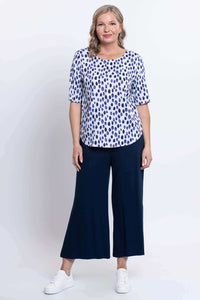 Straight-on view of a woman modeling a blue dapple dot print blouse and navy pants