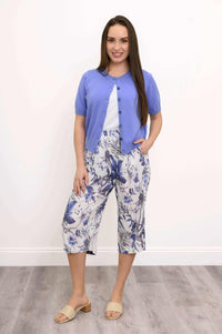 Woman modeling blue floral capri pants with hands in pockets