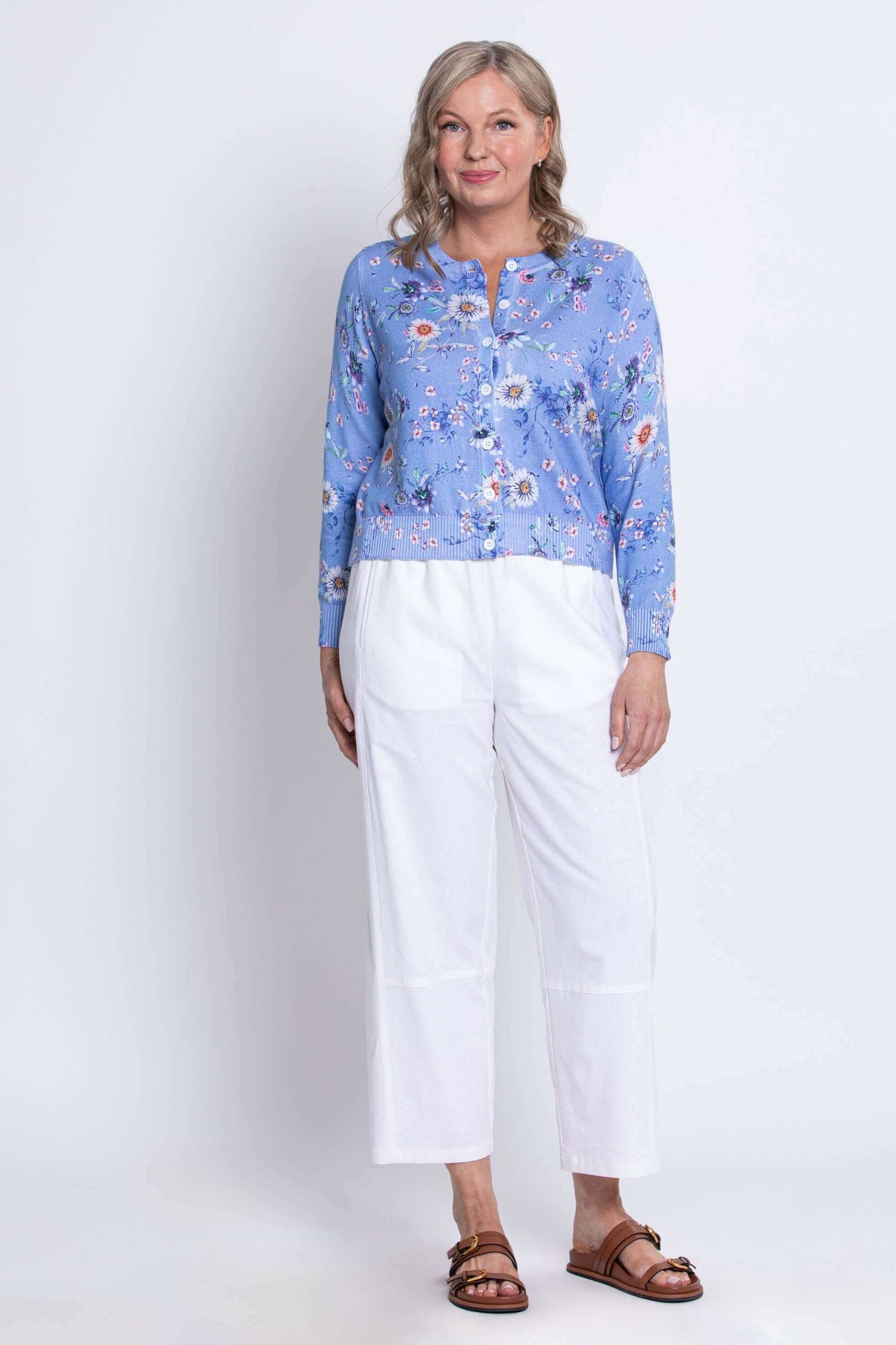 Full front view of woman in a blue floral cardigan and white wide-leg pants