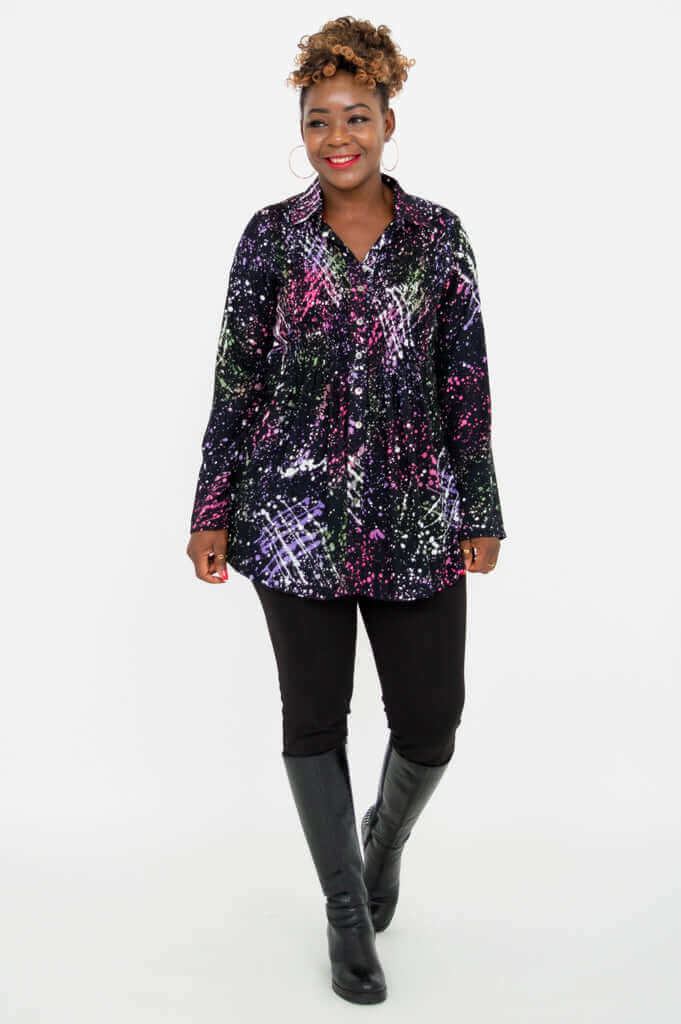 Woman walking forward in a colorful smocked tunic shirt with black leggings and boots