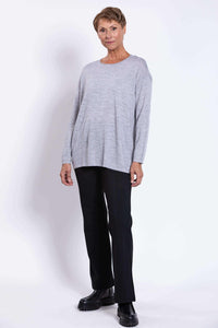 Woman modeling light grey merino sweater and black pants, facing slightly sideways