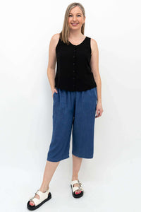 Woman wearing relaxed fit blue denim Tencel capris and black sleeveless top
