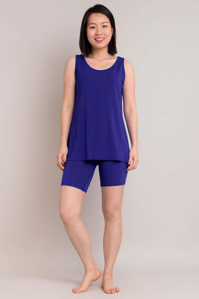 Woman wearing royal blue bamboo shorts and matching top, standing and smiling