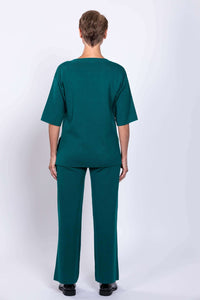 Back view of a woman wearing teal green wide leg knit pants displaying a clean fit and hemline in studio.