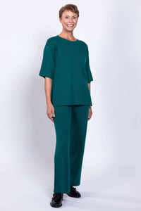 Full length shot of a woman wearing teal wide leg knit pants paired with a matching short sleeve sweater